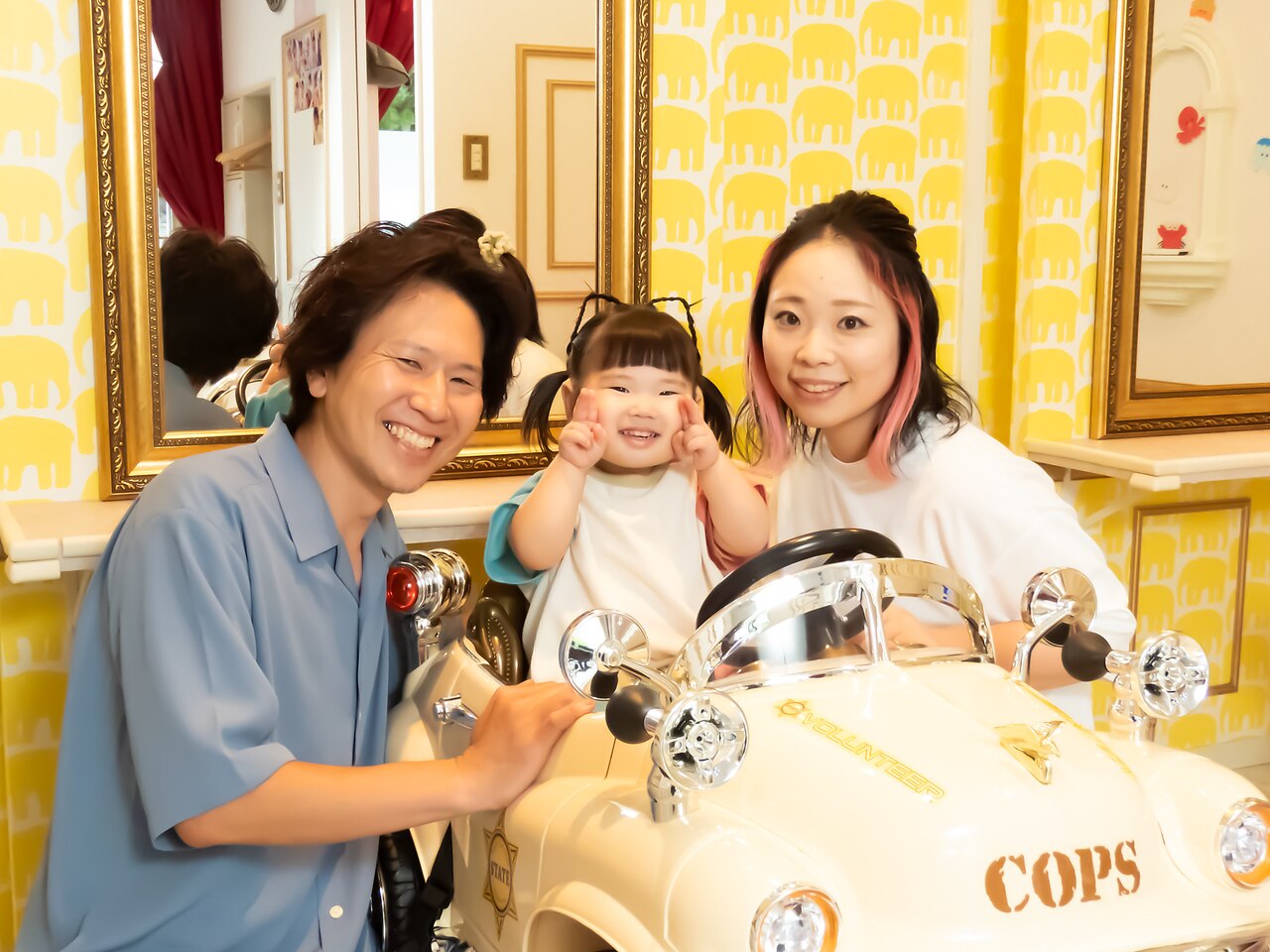 車の椅子を囲んで笑顔のスタイリスト2人とお子さま
